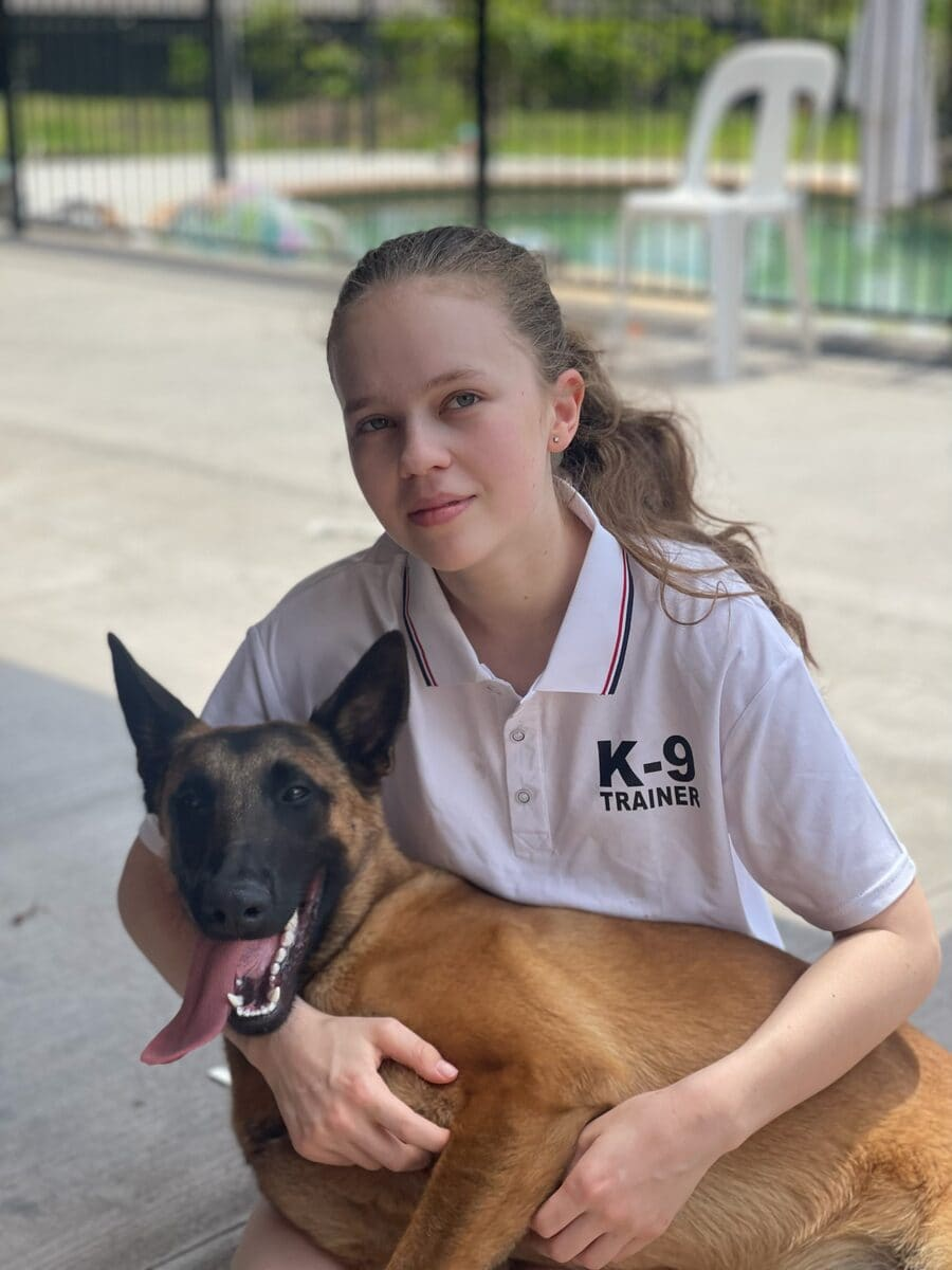 Young K-9 trainer with a calm Belgian Malinois at the Nerang facility